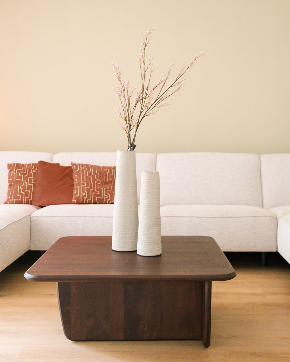 Twee hoge geribbelde vazen in crème kleur op een houten salontafel in een modern interieur