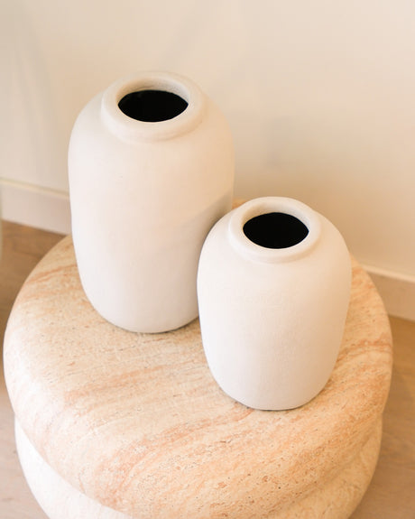 Set van twee beige flesvazen van aardewerk op een natuurstenen kruk in een licht interieur