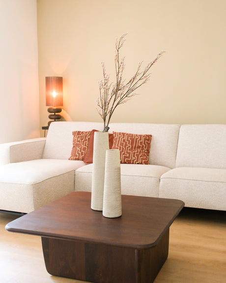 Set van twee hoge geribbelde vazen in crème kleur op een houten salontafel in een moderne woonkamer
